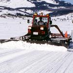 Several districts utilized a DMC with a 14-foot-wide plow blade on the front and a barrel-shaped, grooved drum on the back. The tractor crawled on tracks, pushing the snowplow blades out in front. The blades contoured the snow while the tracks and drum packed it. NPS file photo by Jim Peaco 